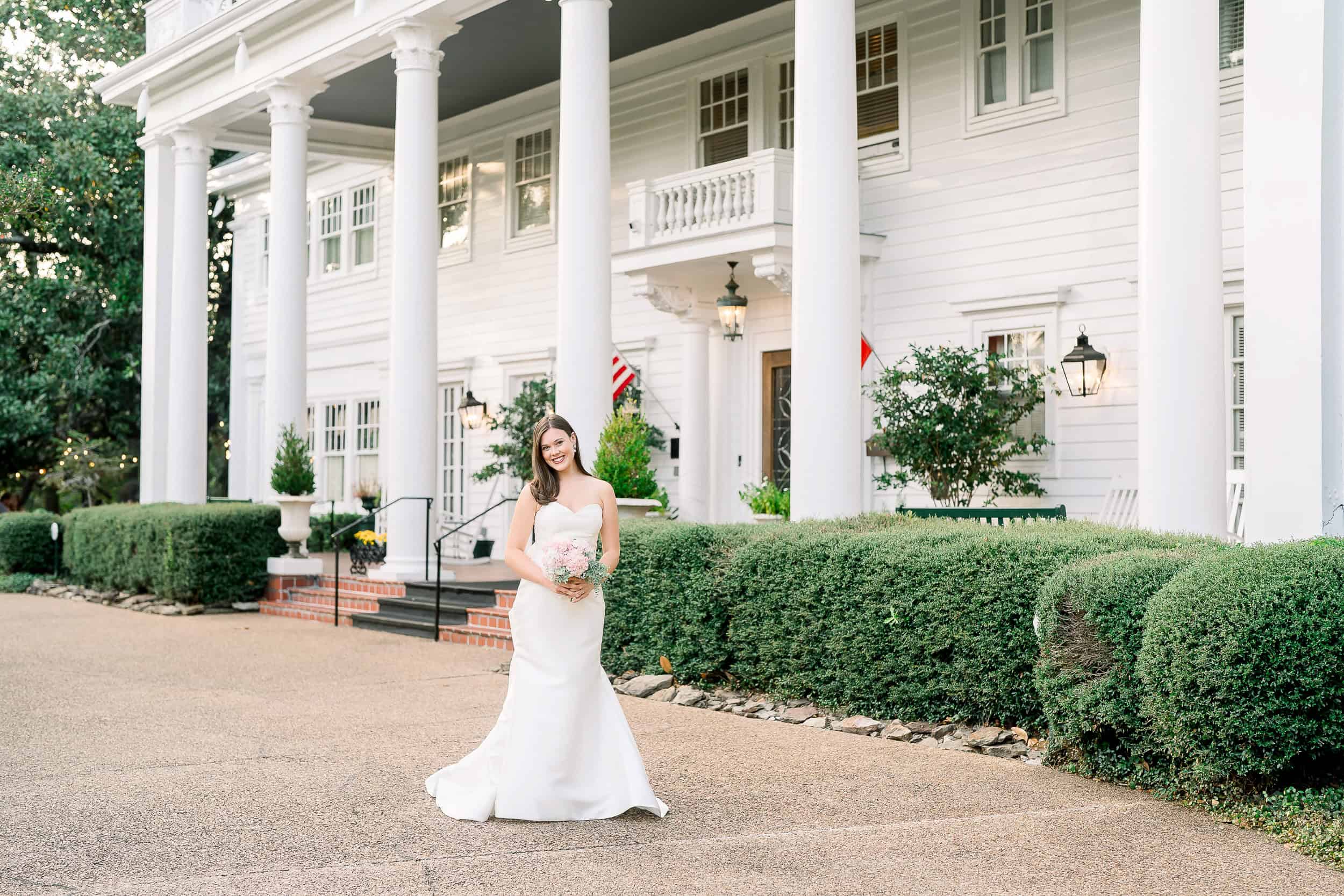 A stunning bride holds her bouquet in front of a historic Jackson, MS mansion at her Fairview Inn Wedding.